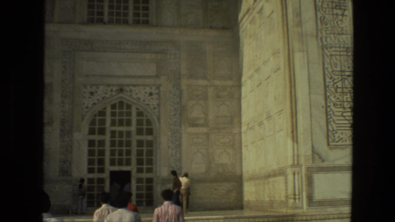 Visitors walk toward an arched doorway beneath carved panels and pale stone walls.