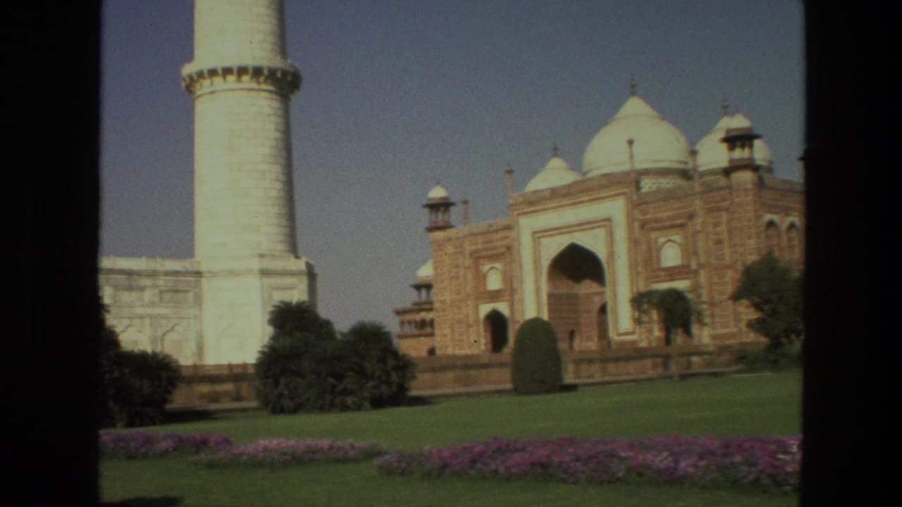 Taj Mahal mosque-side building and minaret seen across lawns and flowerbeds.