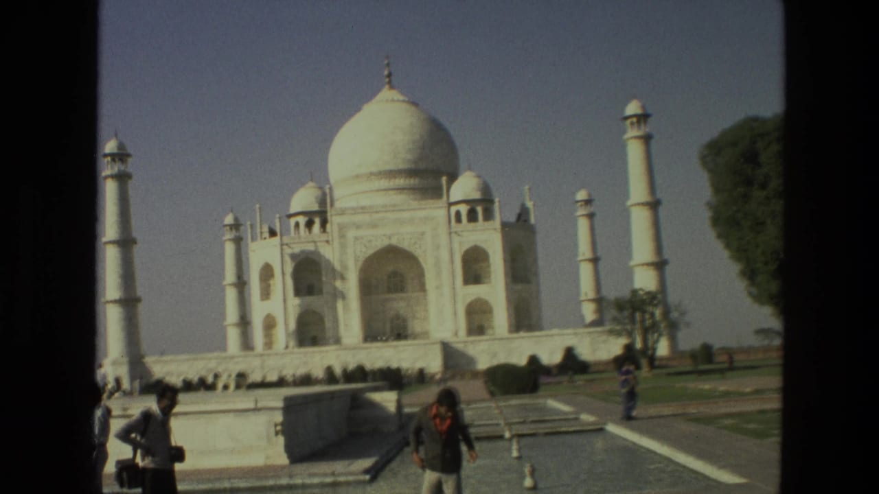 Taj Mahal seen from the gardens with visitors in the foreground and dark film borders.