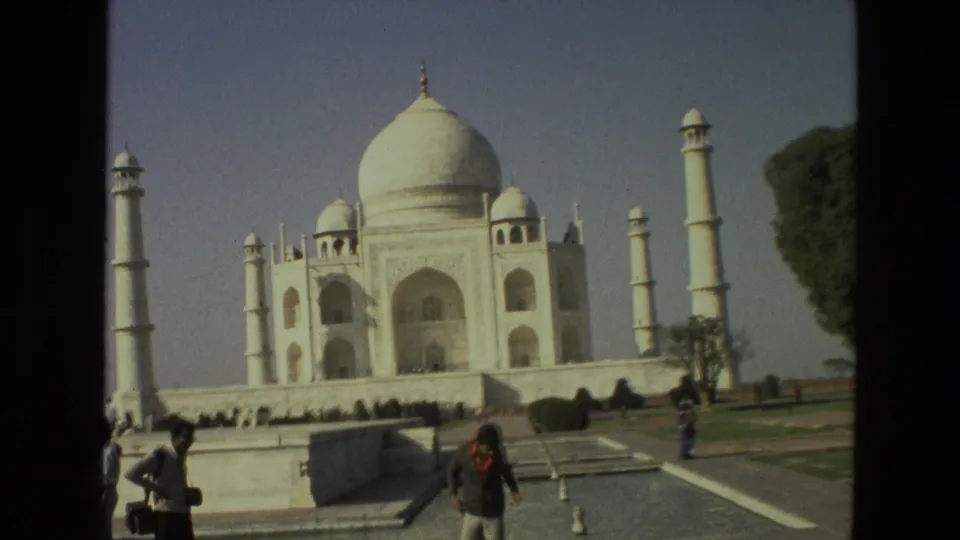 1974 8mm view of the Taj Mahal in Agra, with minarets, lawns, garden paths, and visitors near the foreground.