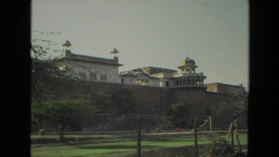 1974 India home-movie view of palace-style architecture behind a wall, with lawns and trees in the foreground.