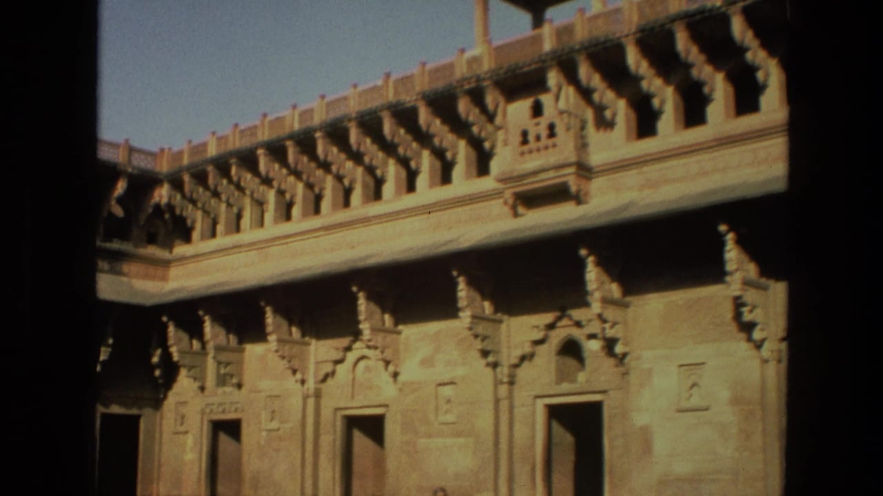 Sunlit carved courtyard wall with doorways and balcony-like stone details.
