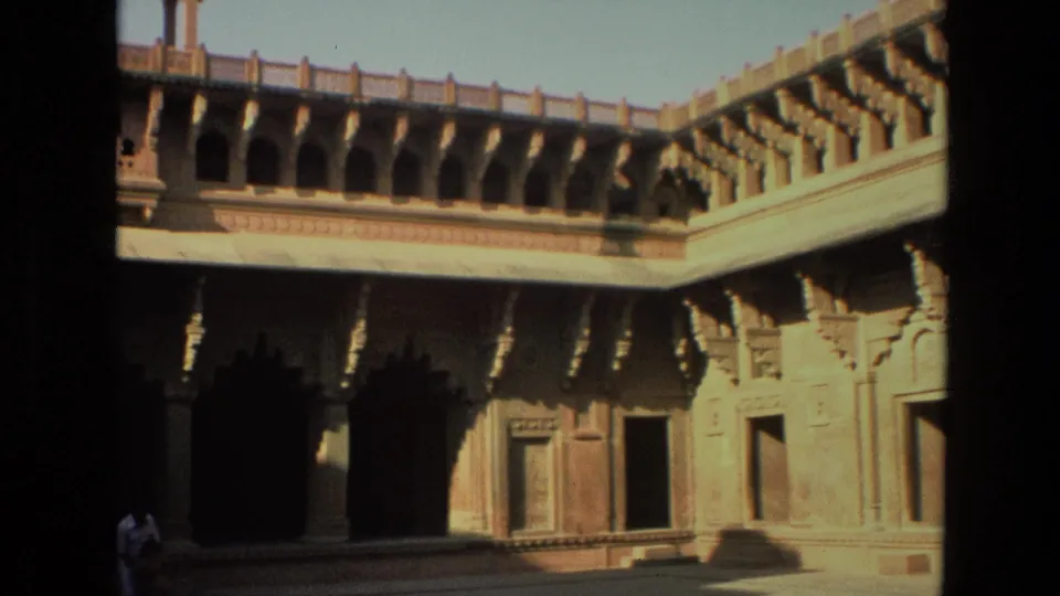 1974 India 8mm frame of a carved shrine courtyard facade, with a small partially visible person near the bottom of the frame.