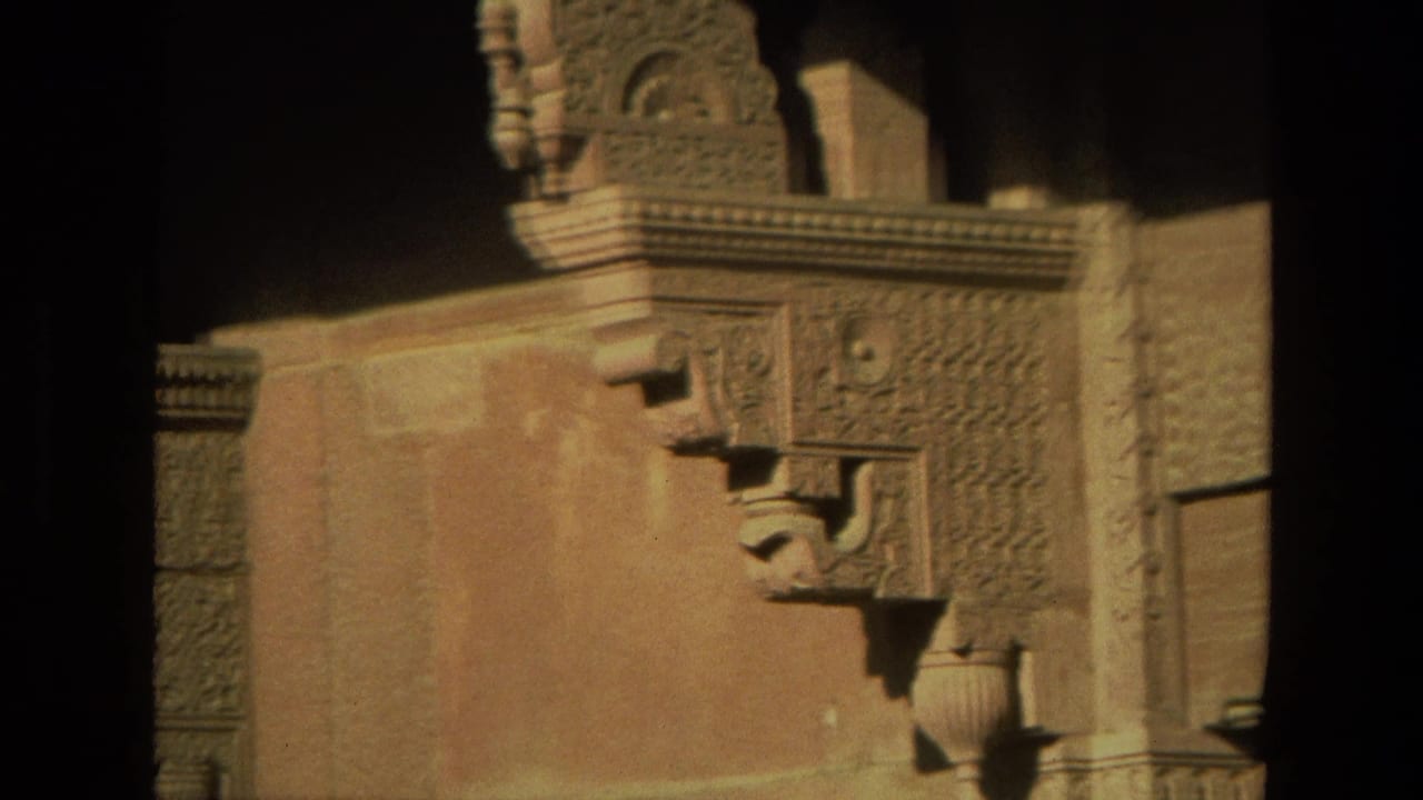 1974 India 8mm frame showing carved stone architectural details, corbels, and a warm-toned wall in soft focus.