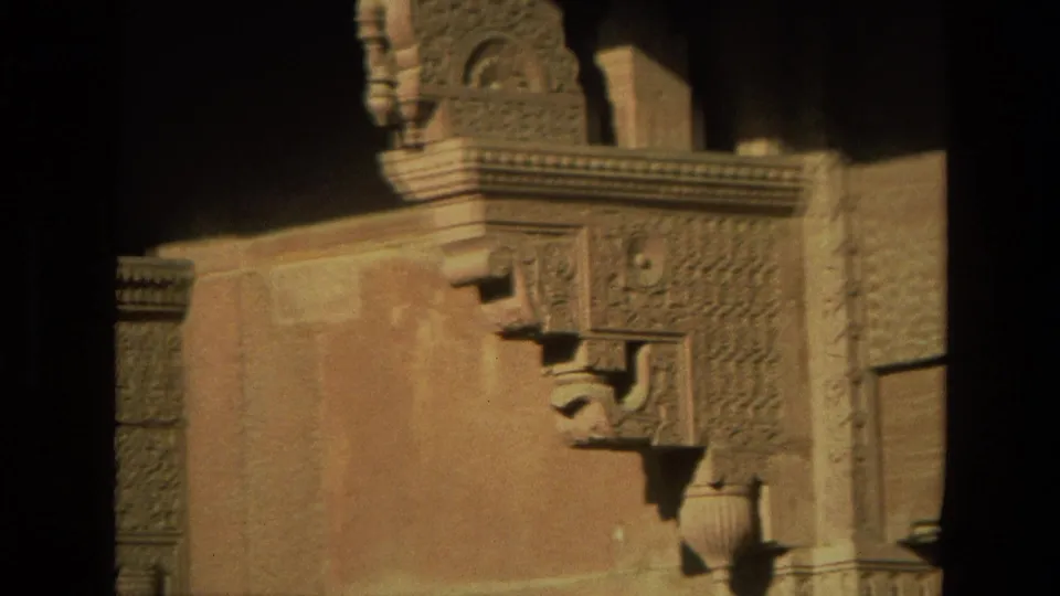 1974 India 8mm frame showing carved stone architectural details, corbels, and a warm-toned wall in soft focus.