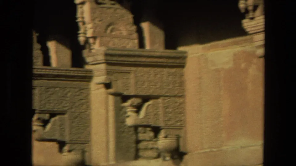 1974 India 8mm frame of ornate stonework, projecting brackets, and a sunlit wall with dark film-frame borders.