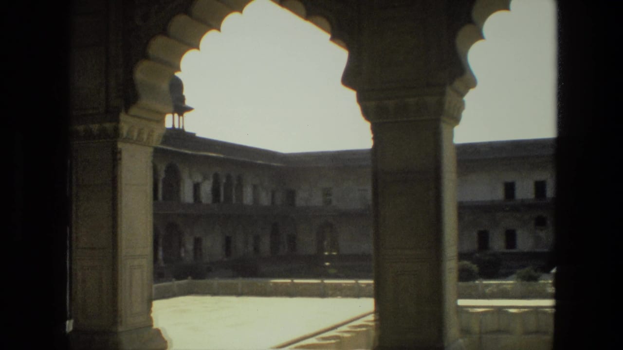 1974 India 8mm frame showing shaded stone arches opening onto a sunlit palace or fort courtyard with upper galleries.