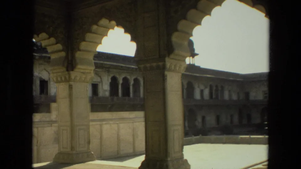 1974 home-movie frame of a carved arch and column overlooking a historic Indian palace or fort courtyard.
