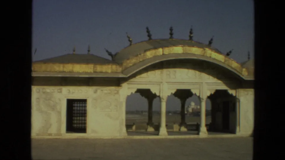 Visitor-shot 8mm view in India showing an ornate pavilion facade and a distant Taj Mahal view through its arches.