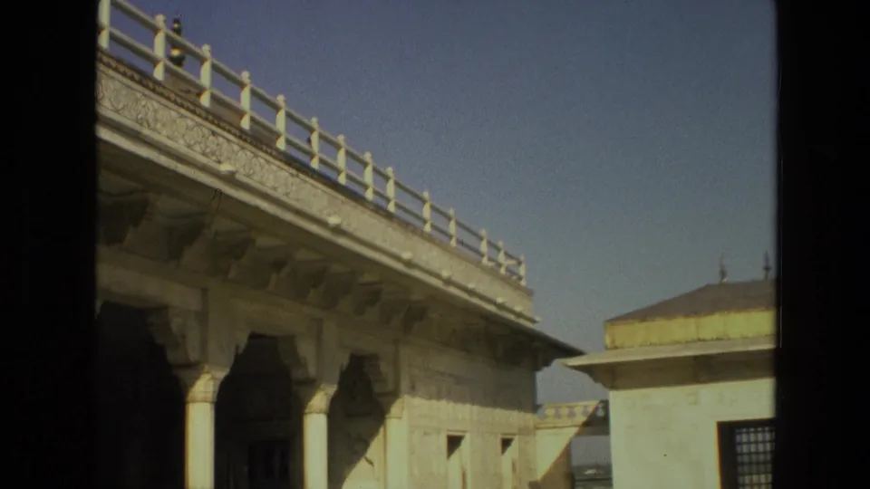 1974 India 8mm frame focusing on a carved elevated walkway, shadowed columns, and a domed marble pavilion beyond.