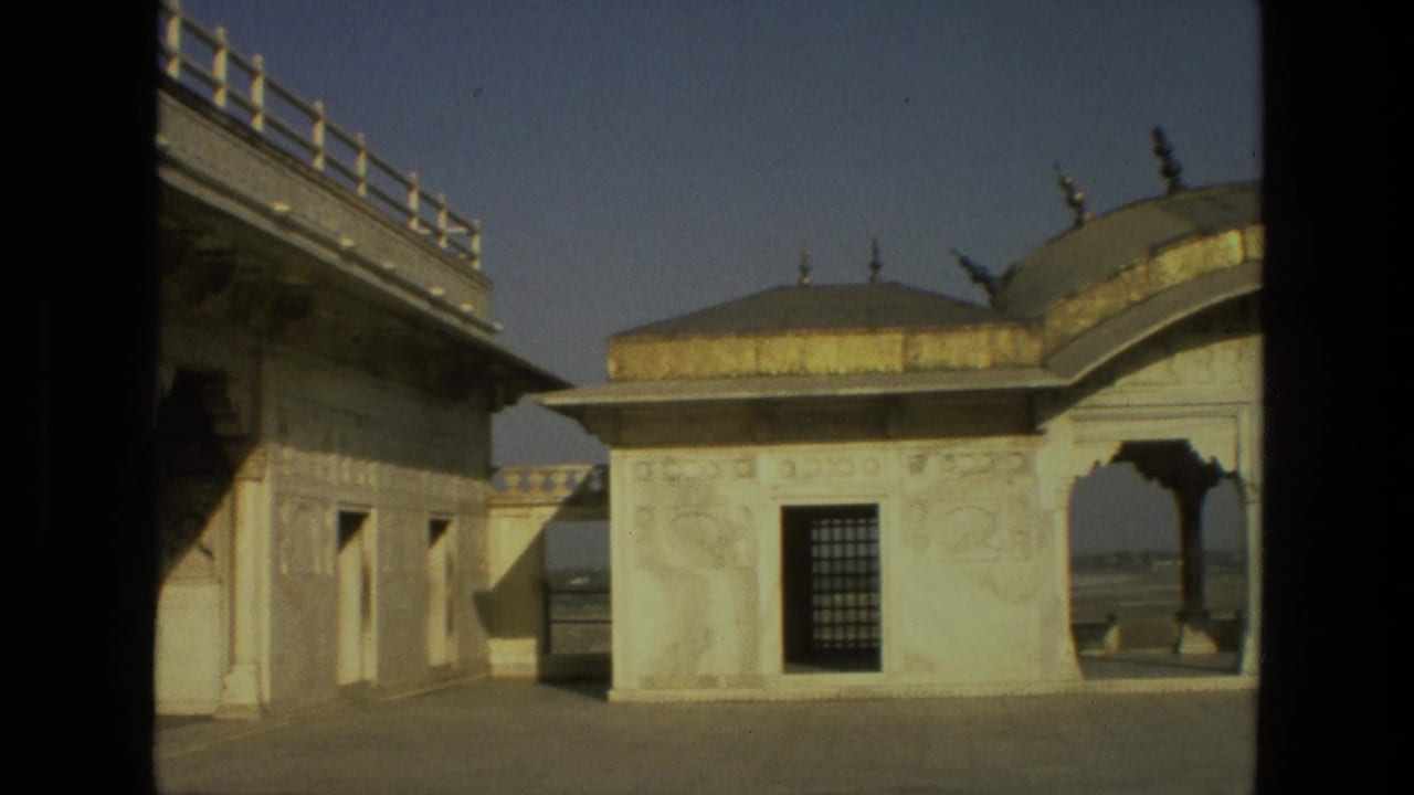 Sunlit ornate pavilion and archway seen from a shaded opening.