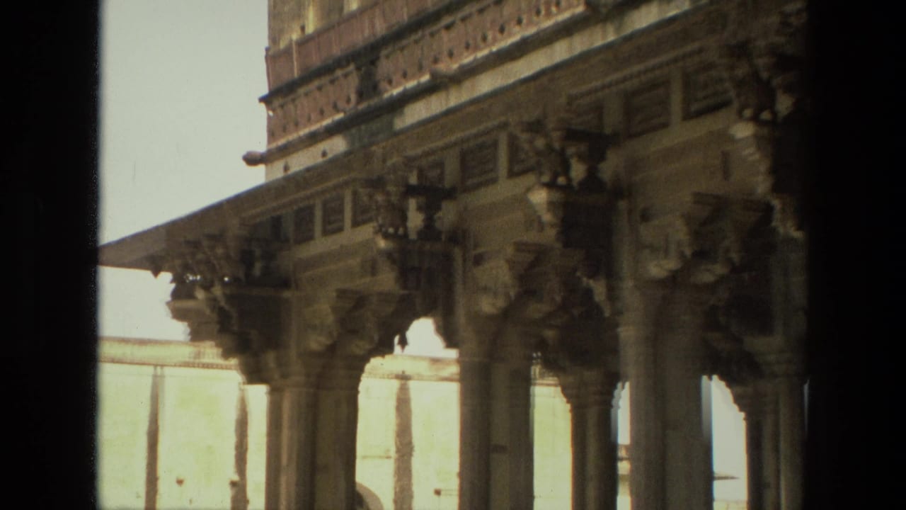 Close view of carved columns and sculptural stone supports under a decorated roofline.