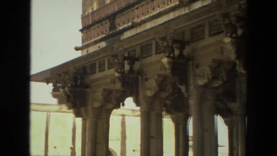 1974 India 8mm view of an ornate monument facade with stone pillars, bracket figures, and patterned horizontal bands.
