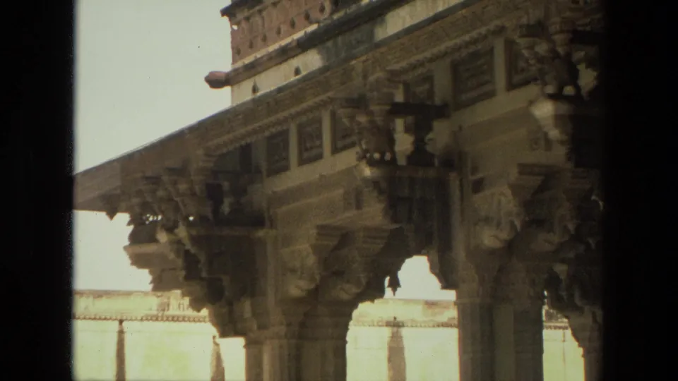 1974 India 8mm frame with an angled visitor view of carved pillars, sculptural details, and a sunlit wall beyond the monument.