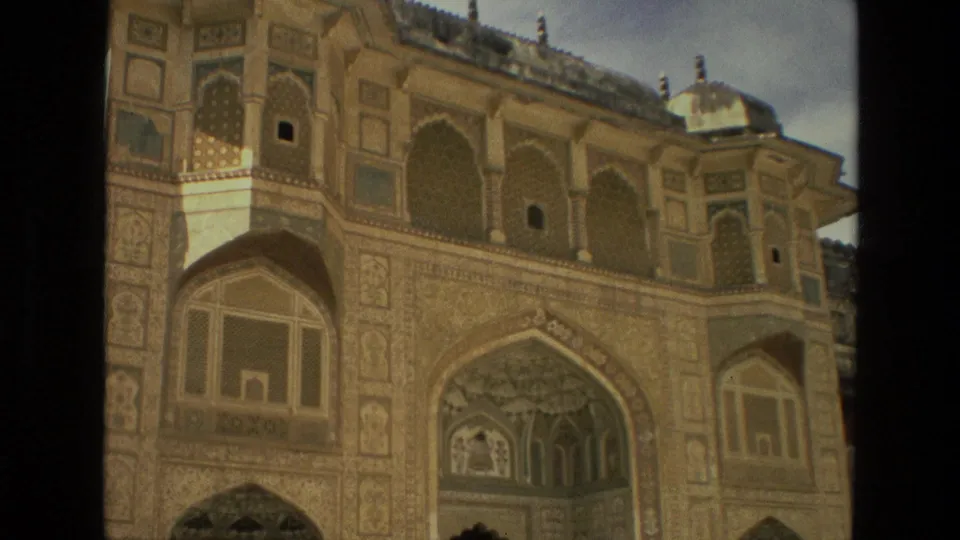 8mm frame from 1974 India showing a historic temple or palace facade with arched niches, patterned panels, and carved stonework.
