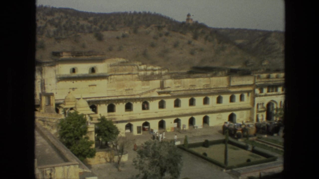 1974 8mm India travel footage showing a cream palace facade, arched openings, dry hills, a garden court, and distant visitors.