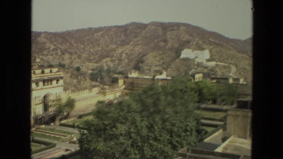 1974 India 8mm view of palace walls, garden terraces, trees, and a white structure on a distant hill.