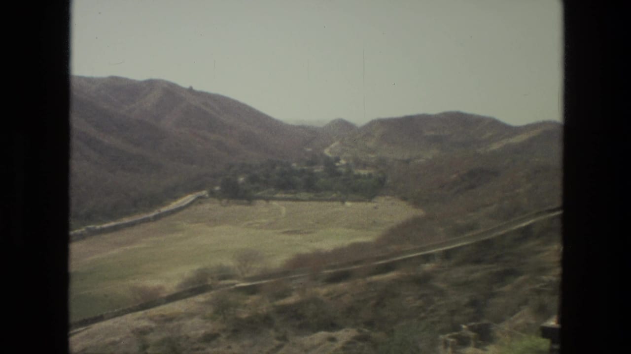 1974 8mm India travel view looking across rolling hills and a valley from an elevated terrace or lookout.