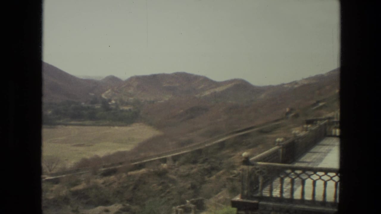 Hillside valley with terrace railing and part of a building at the right edge.