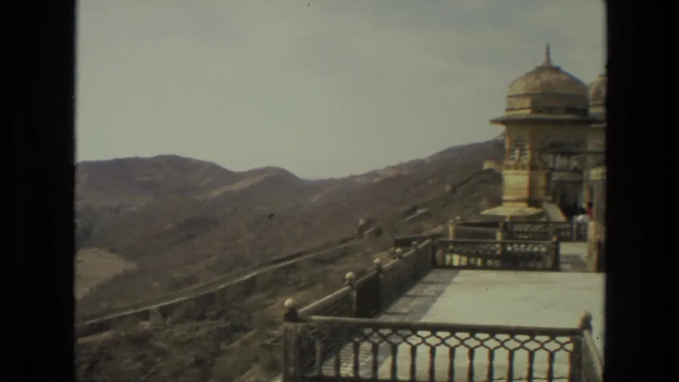 A domed palace or fort structure appears beside a broad terrace, with hills and valley terrain beyond.