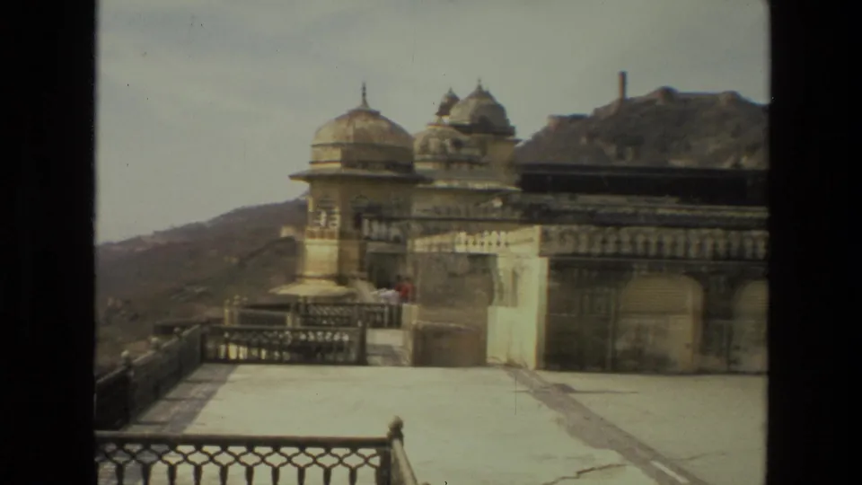 1974 India 8mm frame showing domed palace architecture, weathered walls, lattice railing, and a mountain-side backdrop.