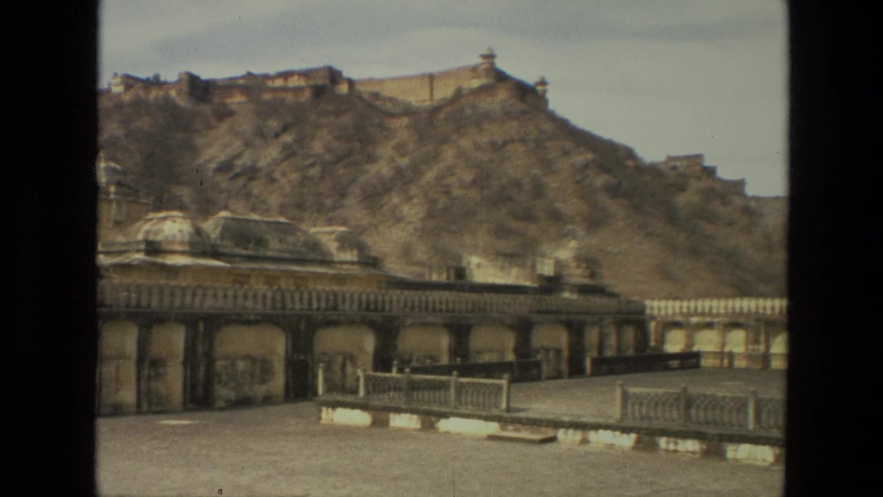 Arched courtyard facade and domed structure at the base of a rocky hill.