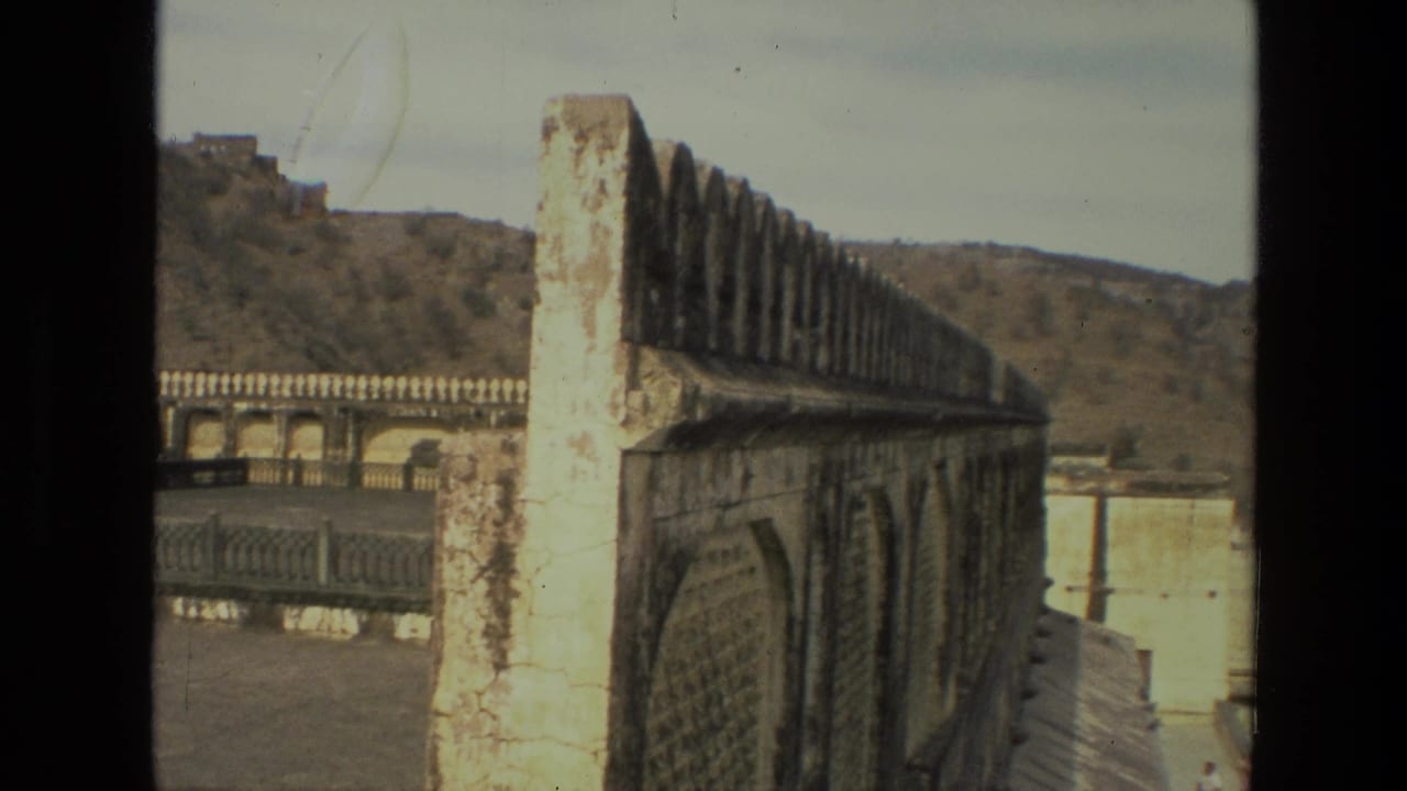 Weathered crenellated palace wall with hills in the background.