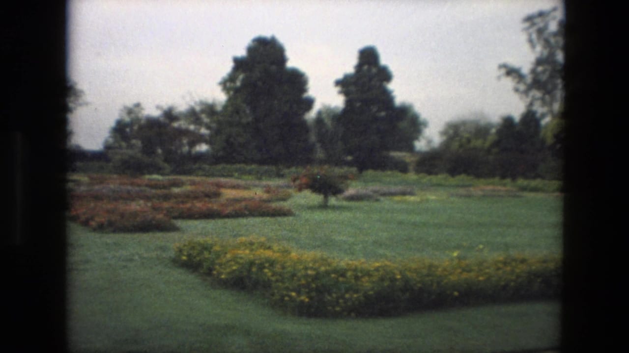 Formal garden with lawns, flowerbeds and trees seen through dark film-frame borders.