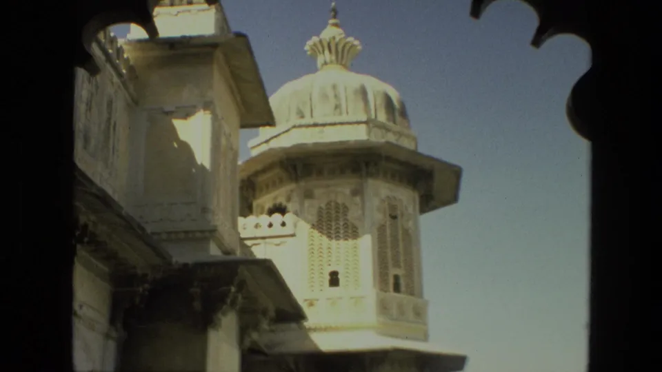 1974 India 8mm frame showing an ornate domed architectural tower with latticework, pale walls, and a decorative arch in shadow.