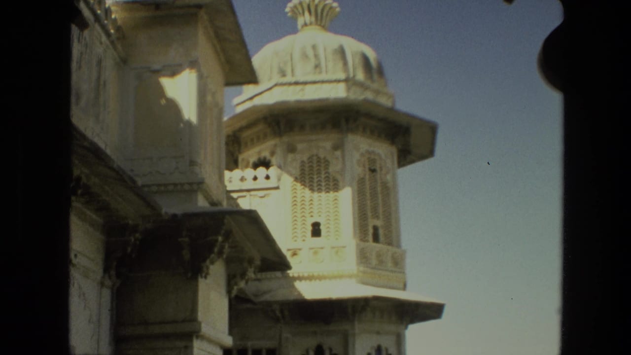 1974 India 8mm frame of an ornate pale stone palace tower with a domed roof, partly framed by dark architectural shadows.