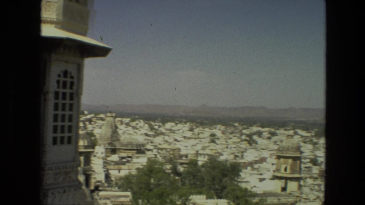 Elevated city view framed by a stone structure and distant hills.