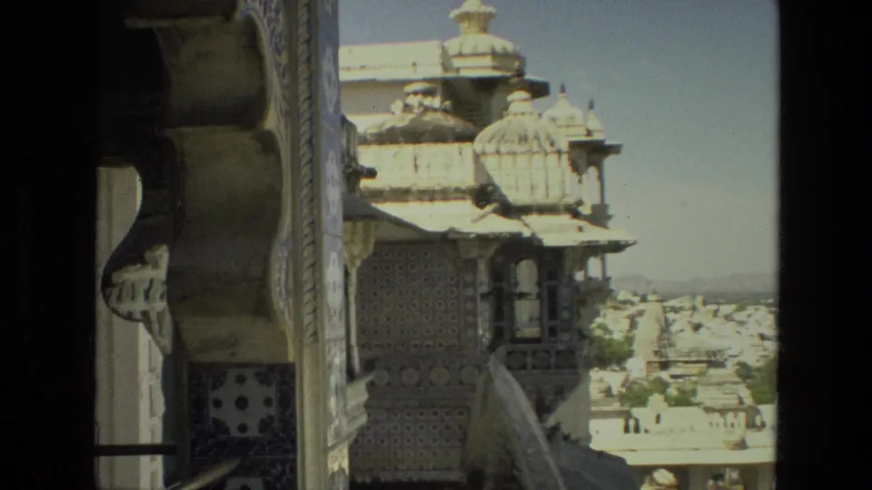 1974 India frame with patterned tilework, a small projecting balcony, domed rooflines, and a cityscape beyond.