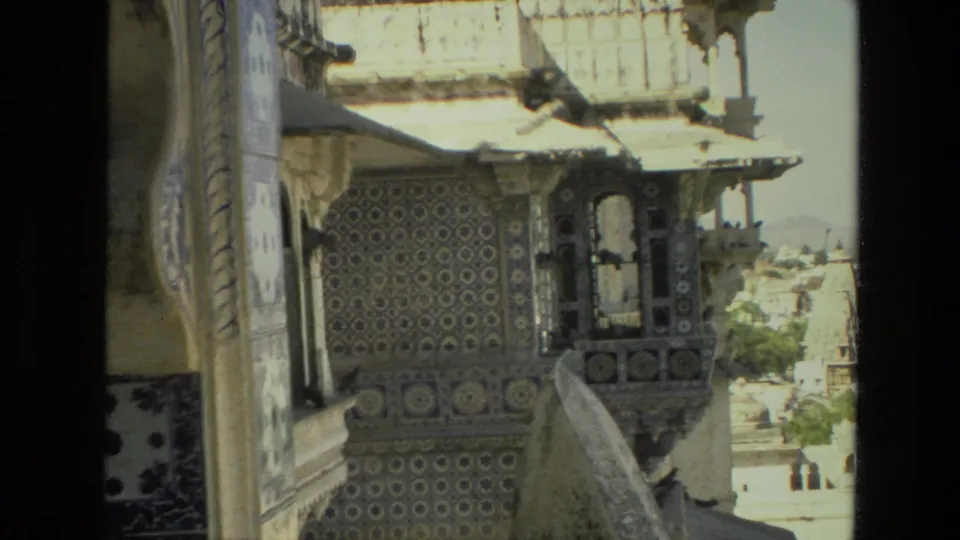 1974 India 8mm frame showing ornate blue and white tilework, pale stone railings, and arched balcony details from a visitor viewpoint.
