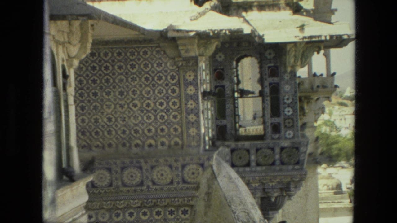 1974 India 8mm frame closer on an ornate palace balcony, with patterned tile panels, arched openings, and birds perched near the ledge.