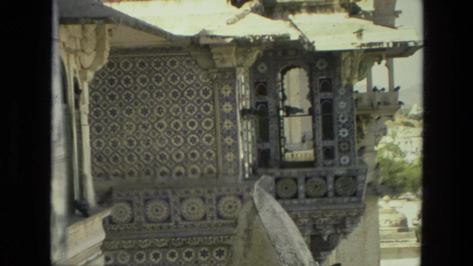 1974 India 8mm frame closer on an ornate palace balcony, with patterned tile panels, arched openings, and birds perched near the ledge.