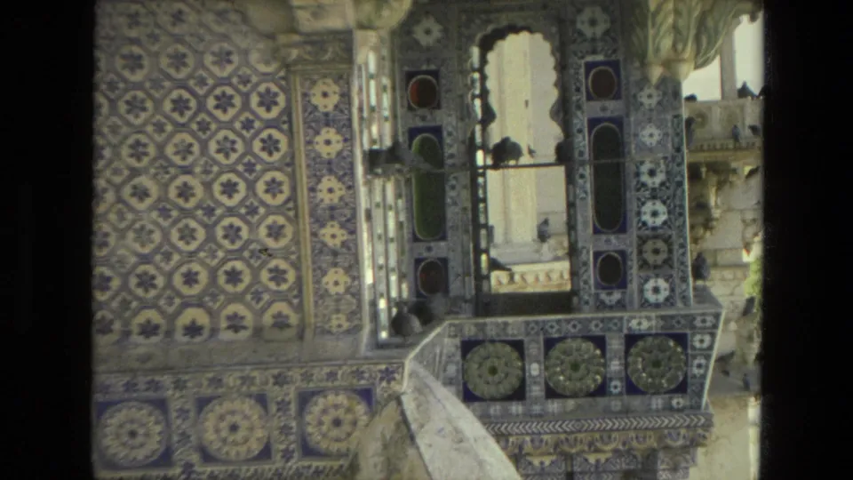 Close 1974 India 8mm view of blue and white palace tilework, mirrored-looking trim, a small balcony ledge, and birds near the opening.