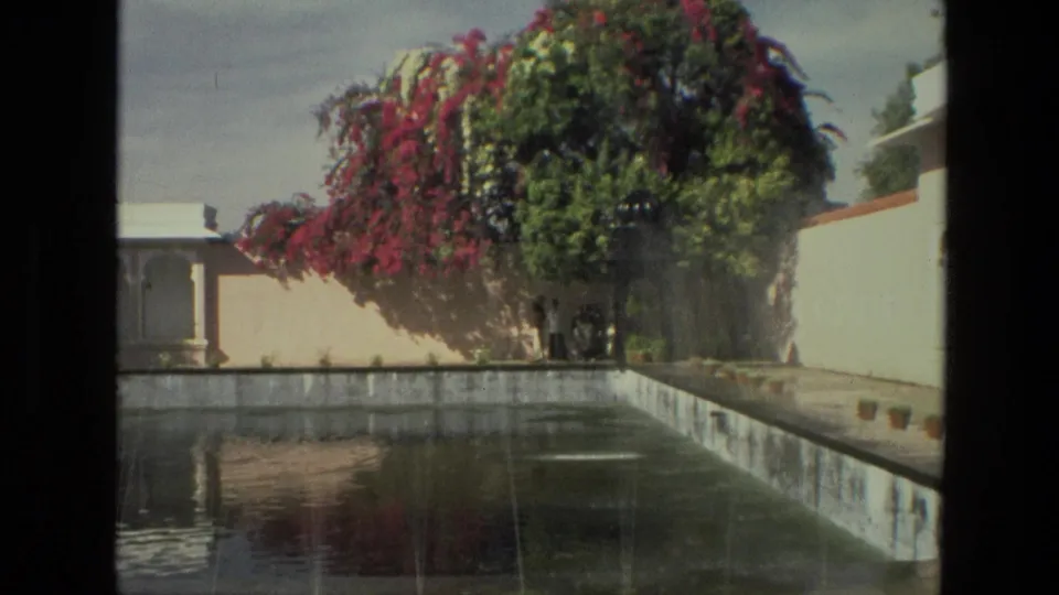 A 1974 India courtyard view shows a long reflecting pond, white walls, arched architecture, and flowering bougainvillea above the walkway.