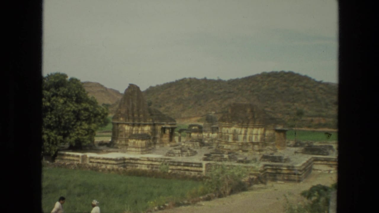 Stone temple structures with spires set near fields and hills.