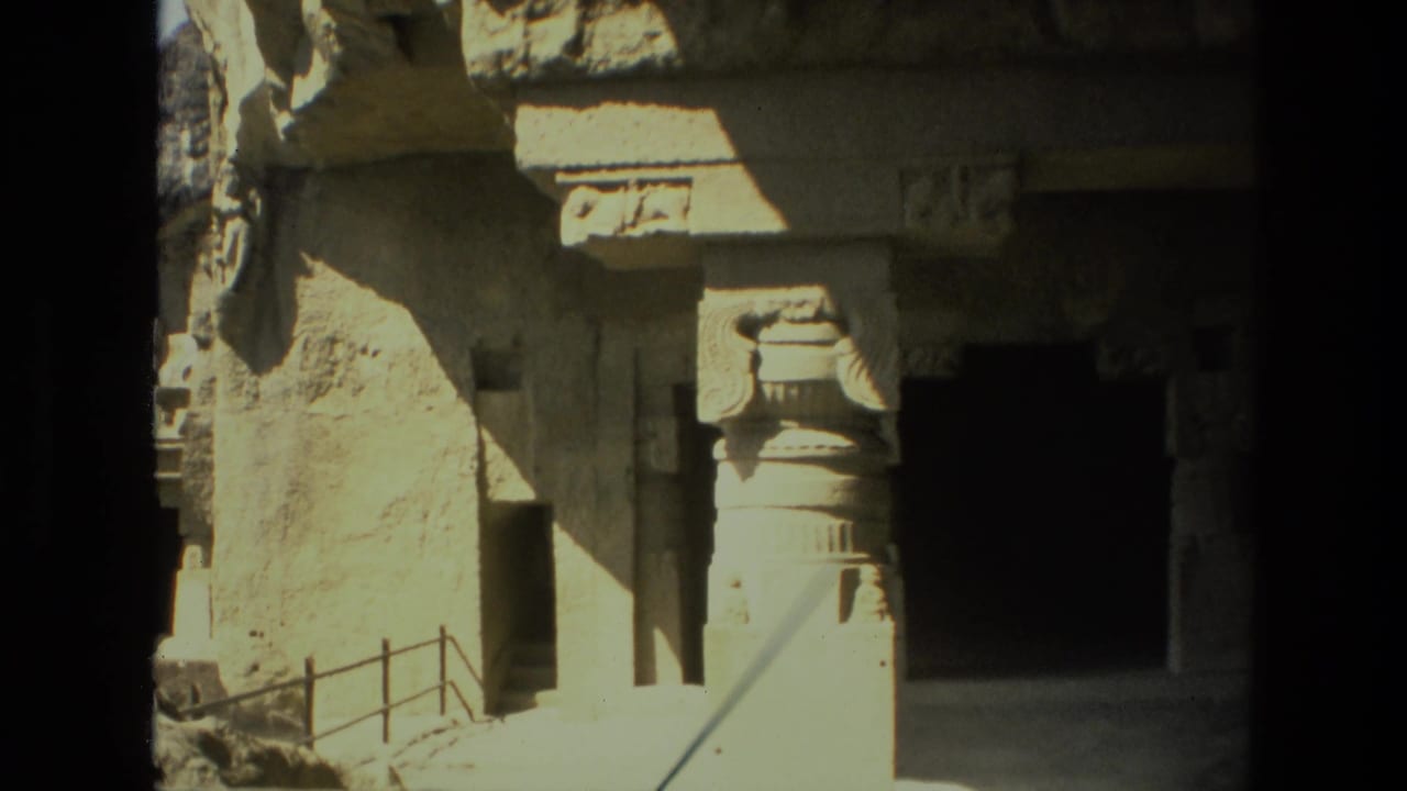 Sunlit stone pillars and a dark cave doorway are framed close to the entrance.