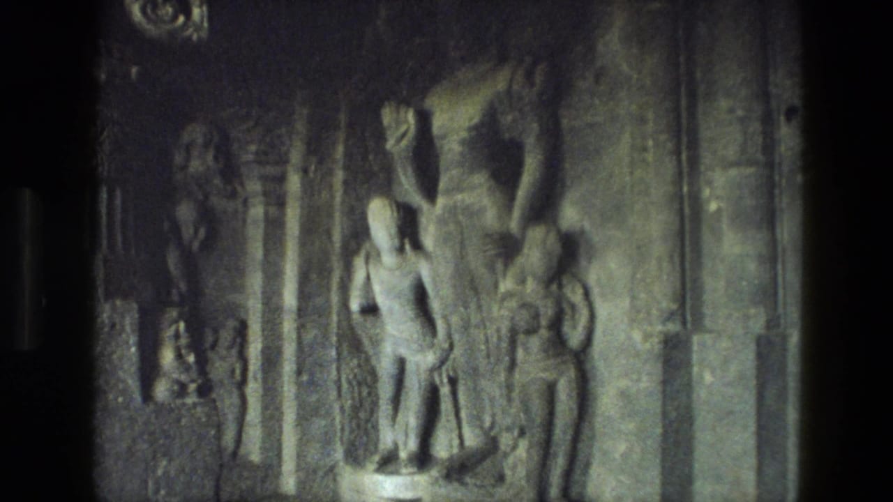 Stone relief figures carved into a dark temple wall beside vertical pillars.