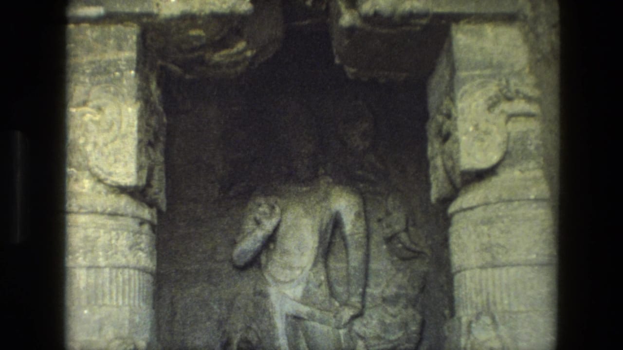 Carved standing figure on a stone wall framed by ornate pillars.