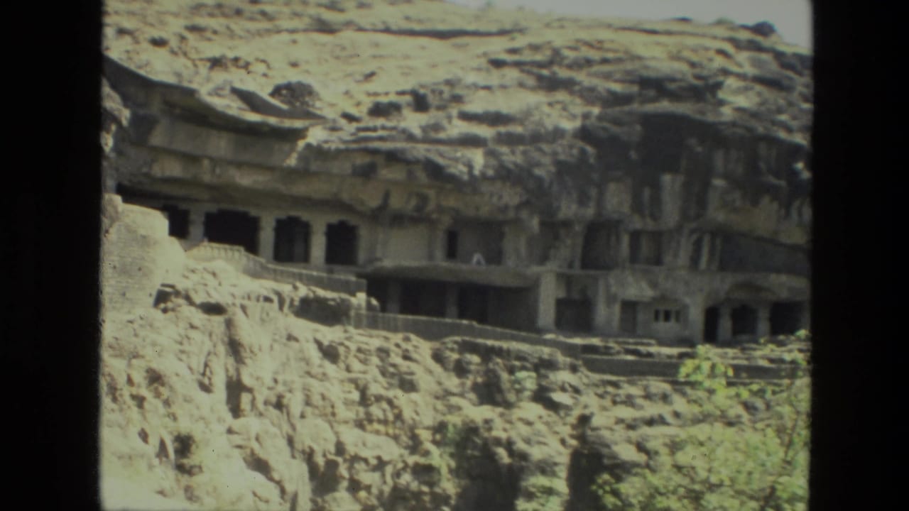Rock-cut cave openings and ledges carved into a rugged cliff face.