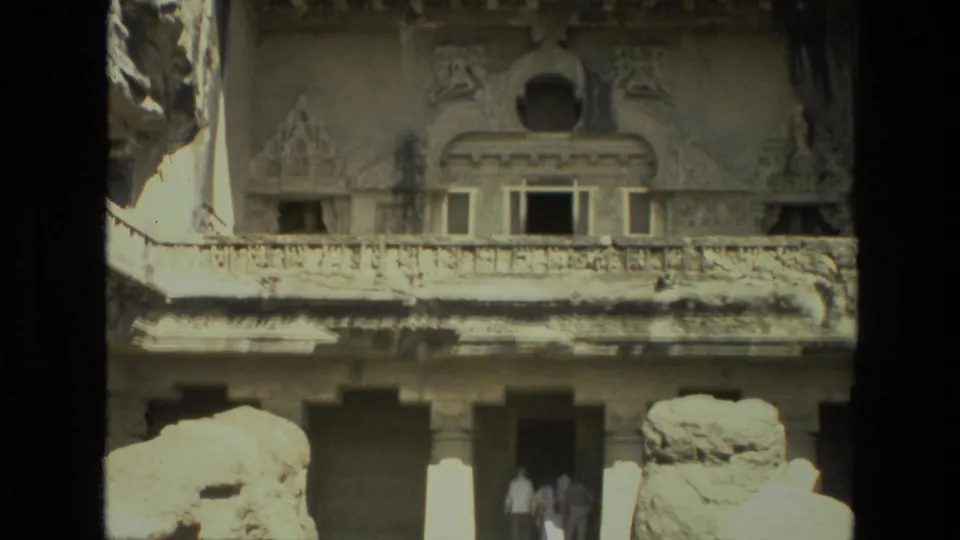 1974 India 8mm frame of a monumental carved stone exterior with a few distant visitors near the lower entrance area.