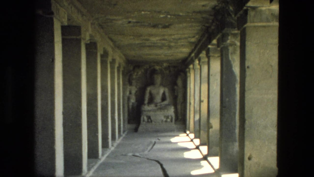 1974 India 8mm frame of a weathered temple passage with rectangular sunlight patches and a seated religious figure at the end.