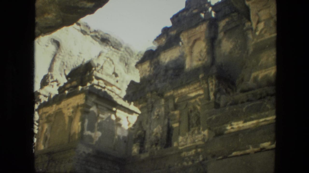 Weathered carved stone structure with columns and dark film borders.