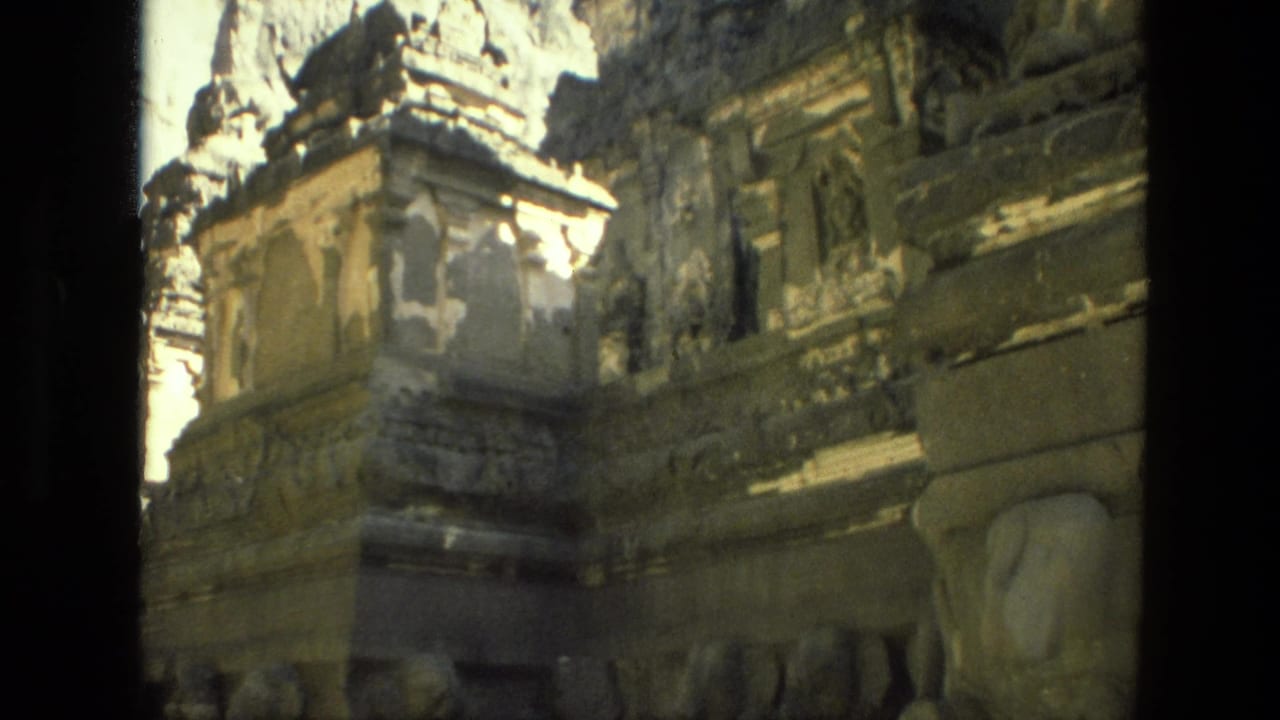 1974 India home-movie frame showing ornate, worn stonework with ledges, column forms, and dark recesses.