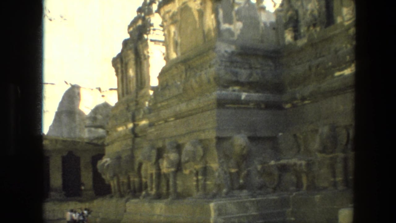 Carved stone ruin wall and columns seen in bright sunlight.