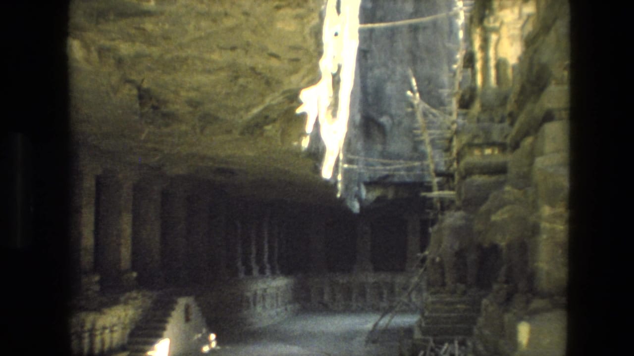 1974 India 8mm interior view showing shadowed stone columns, railings, rough rock surfaces, and scaffolding.