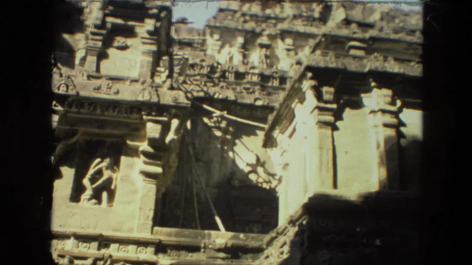 1974 India 8mm frame of a carved stone temple facade with pillars, recessed openings, and weathered sculptural details.