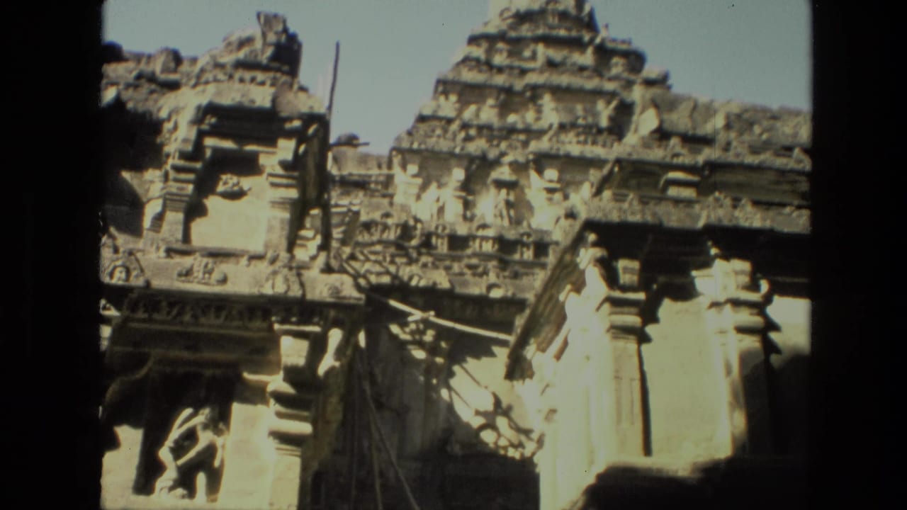 1974 8mm view in India looking up from a shaded archway toward carved stone temple towers and pillars.